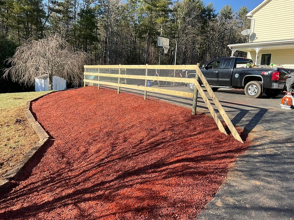 A fresh mulch bed and new wood fence line installed by Cavalier Cleanup