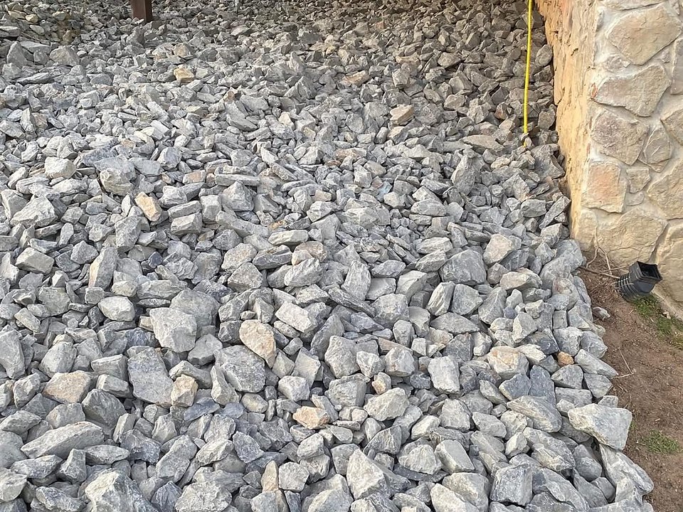 Fresh crushed gray stone spread and graded along a foundation by Cavalier Cleanup